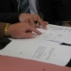 Gros plan sur des mains pointant un document, pour illustrer la réforme en droits des contrats