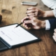 Gros plan sur les mains d'entrepreneurs installés autour d'une table devant un contrat